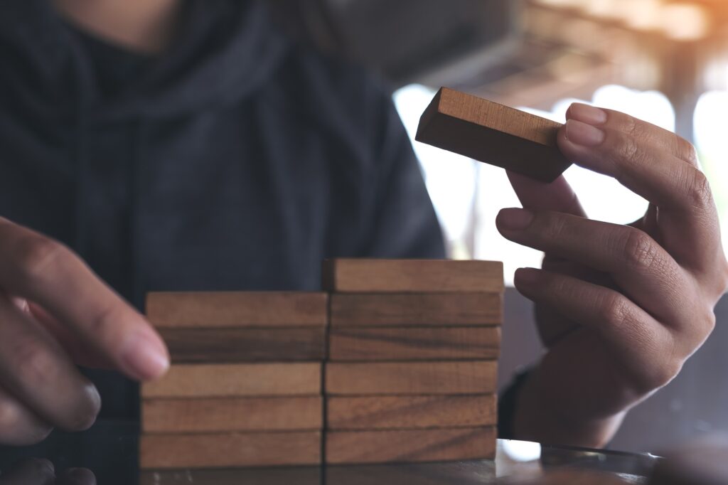 Closeup image of people playing and building wooden puzzle game